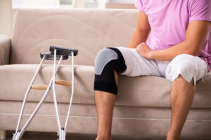 Young man with injured knee recovering at home